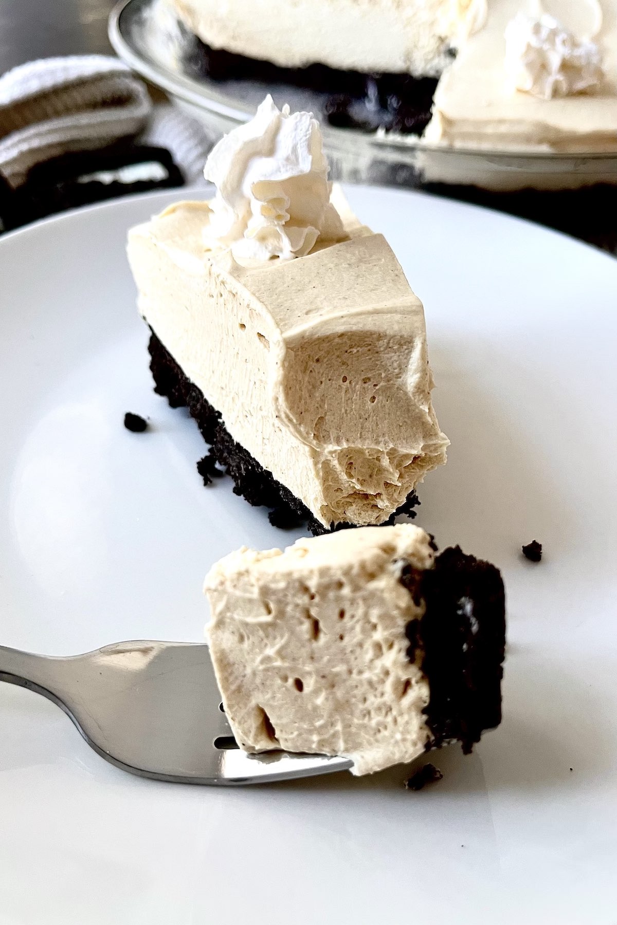 A slice of no bake peanut butter pie with oreo crust on a white plate.
