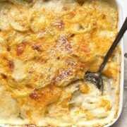 Mom's old fashioned scalloped potatoes in a white baking dish next to a beige linen towel.