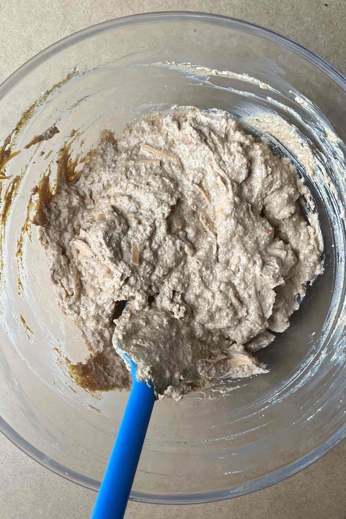 Sour cream, cream cheese, taco seasoning, refried beans, and shredded cheese mixed in a bowl.