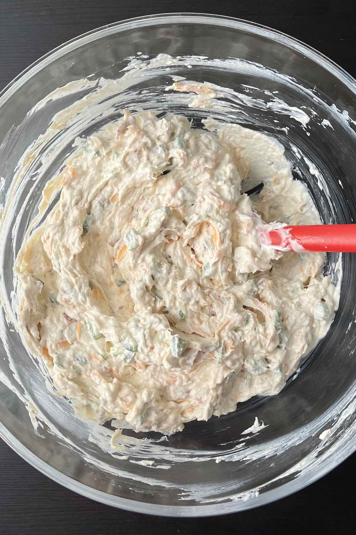 Diced green pepper, bacon pieces, shredded rotisserie chicken, and shredded cheddar cheese mixed with the bowl of other ingredients.