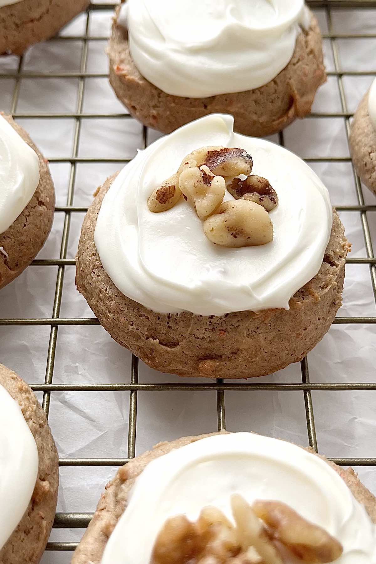 Carrot cake mix cookies with cream cheese icing scattered on a cooling rack.