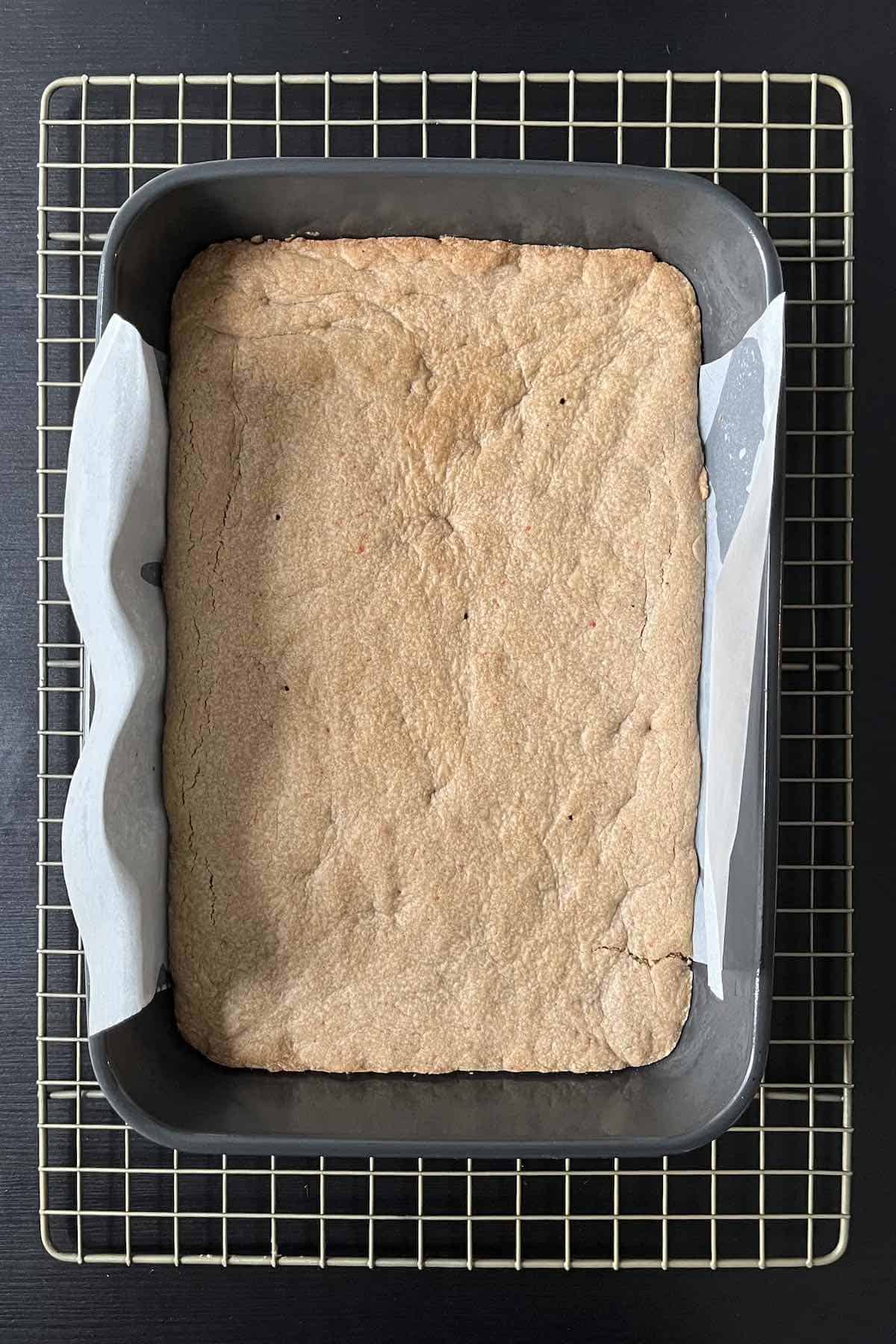 Baked carrot cake bars in a baking dish on top of a cooling rack.