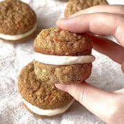 Hand holding a carrot cake sandwich cookie.