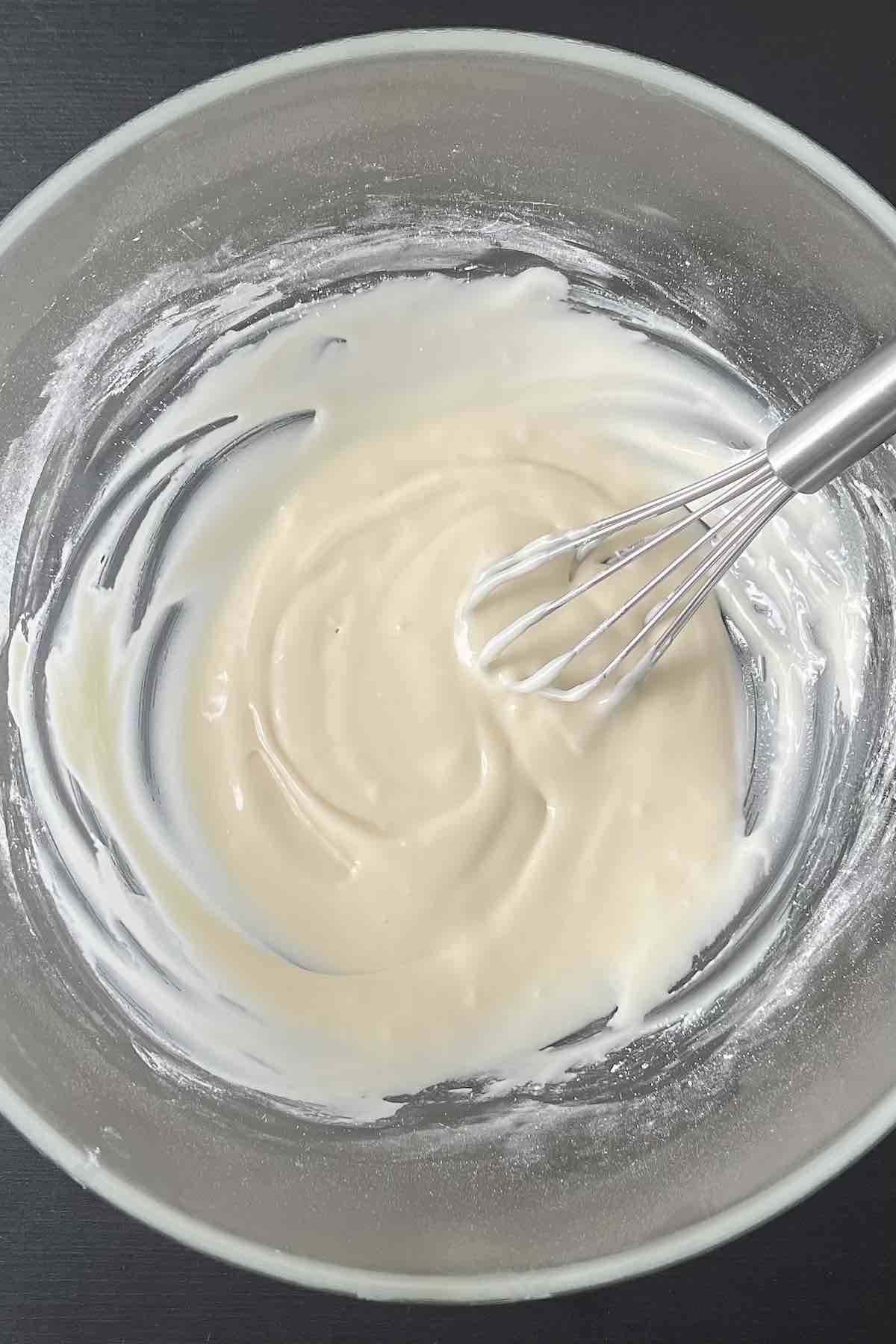 Cream cheese, milk, vanilla, and icing sugar combined in a bowl. 