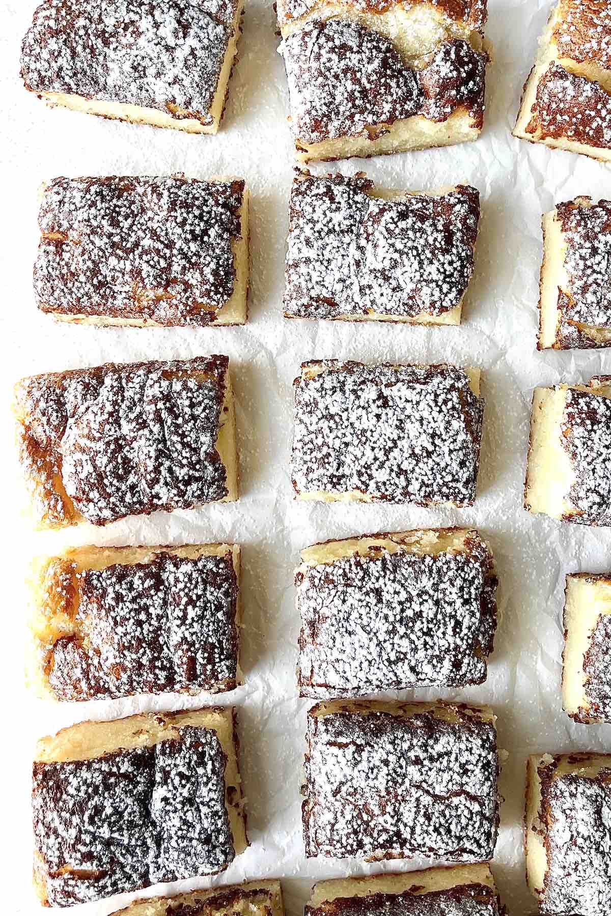 Two ingredient lemon bars with angel food cake mix scattered on a piece of white parchment paper.
