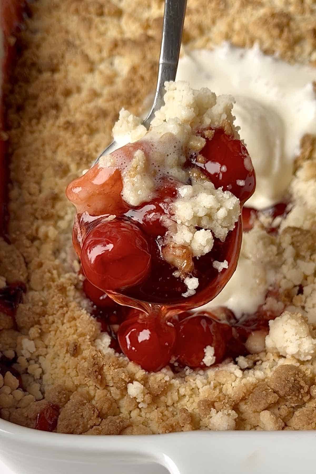 Spoon with a scoop of cherry cobbler on it.