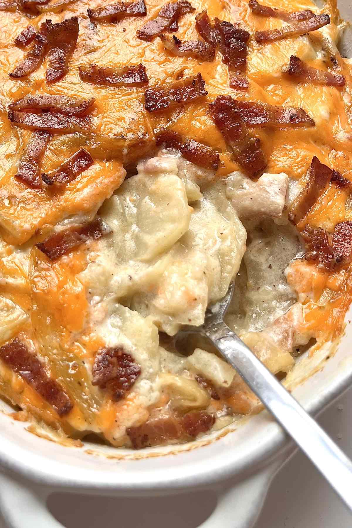 Spoon in a bowl of loaded scalloped potatoes.