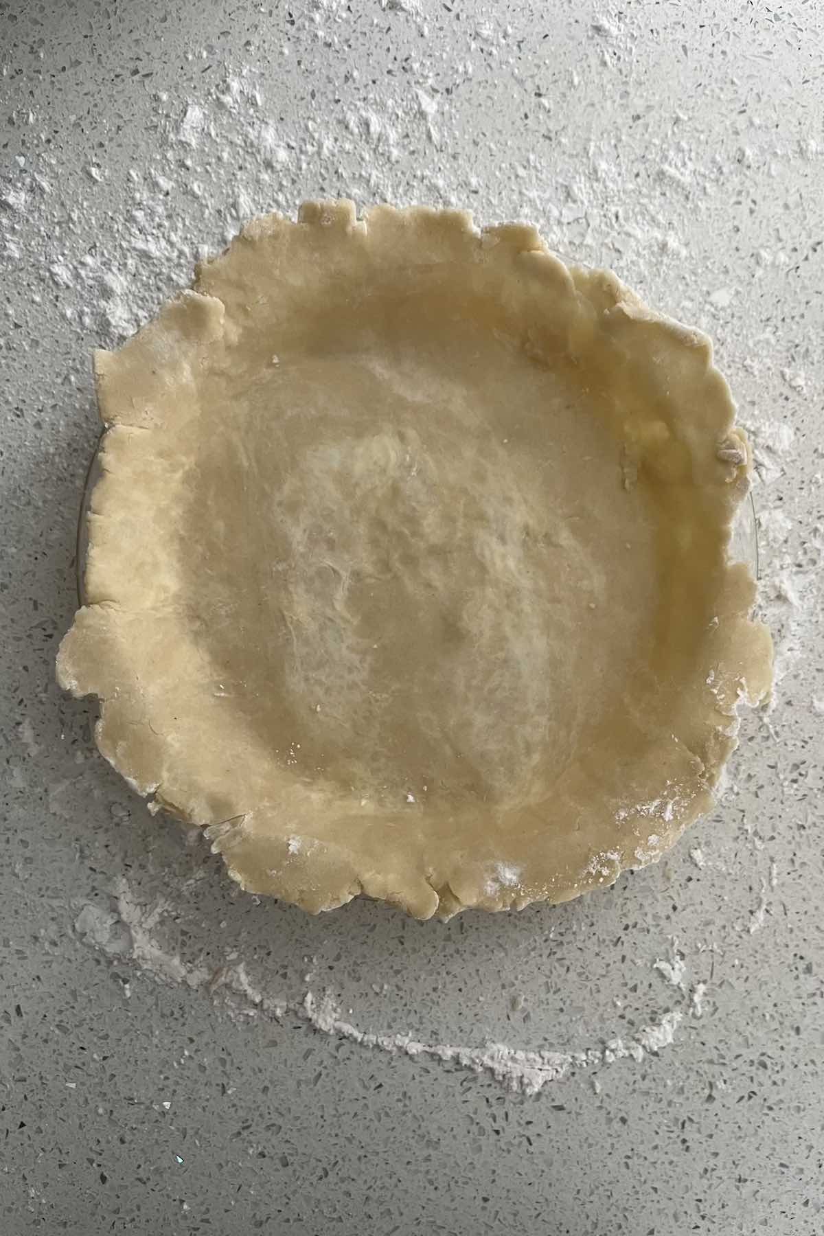 Pie dough unraveled in the pie dish.