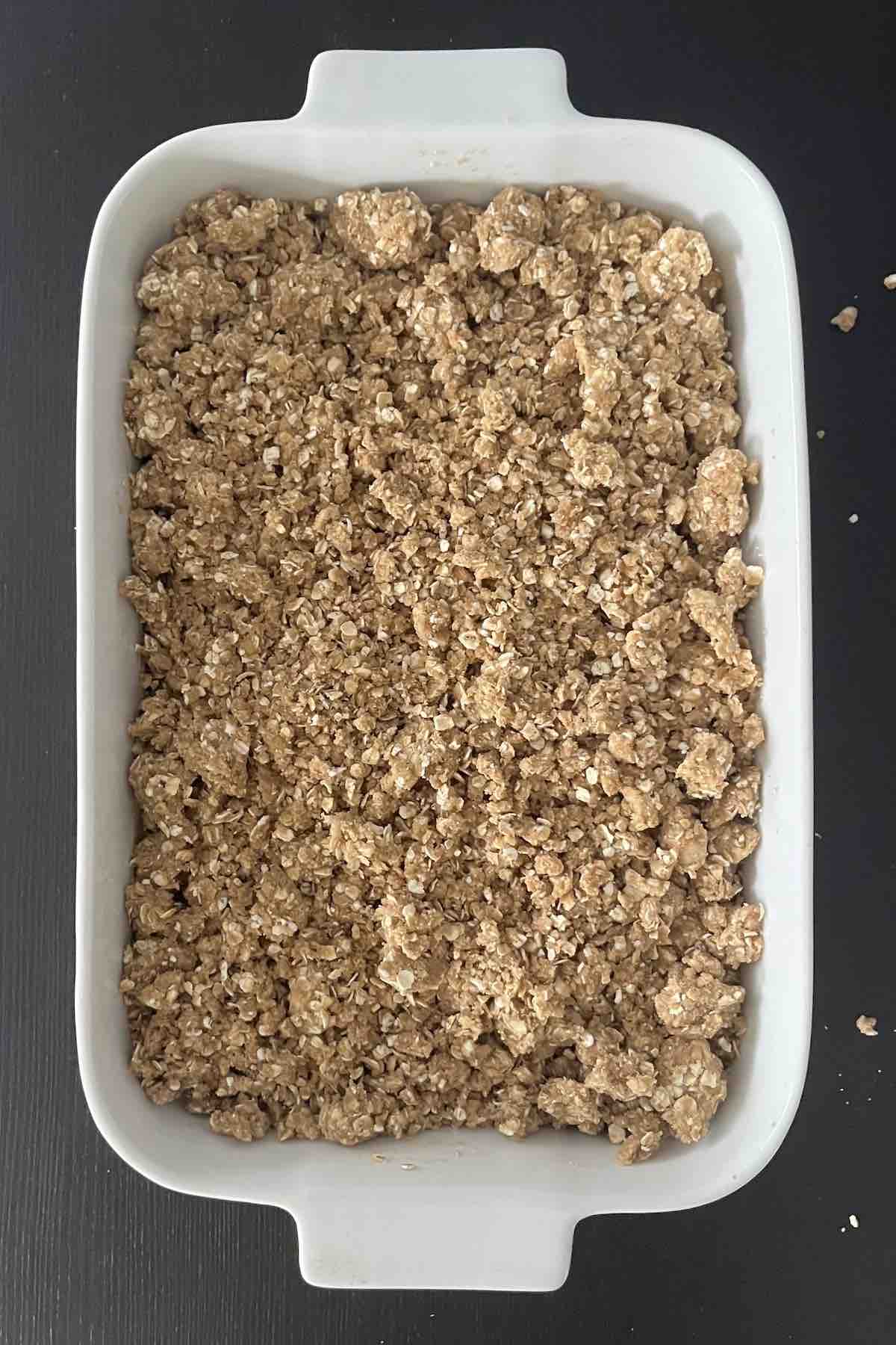 Crisp topping on top of the apple filling in the casserole dish ready to be baked.