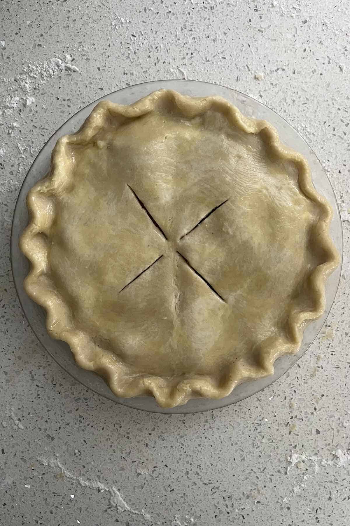 Edges of the pie crimped with slits in the top and brushed with egg wash.