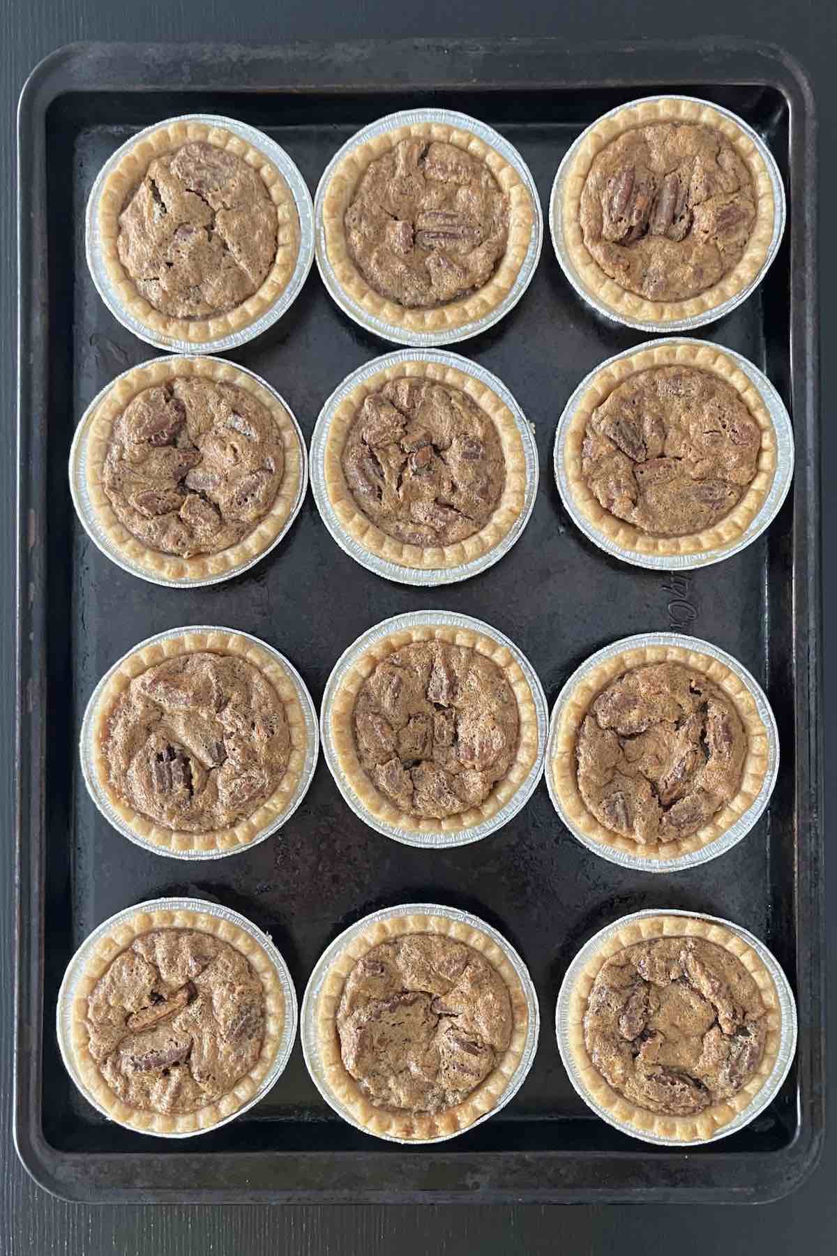 Baked pecan butter tarts on a baking sheet.