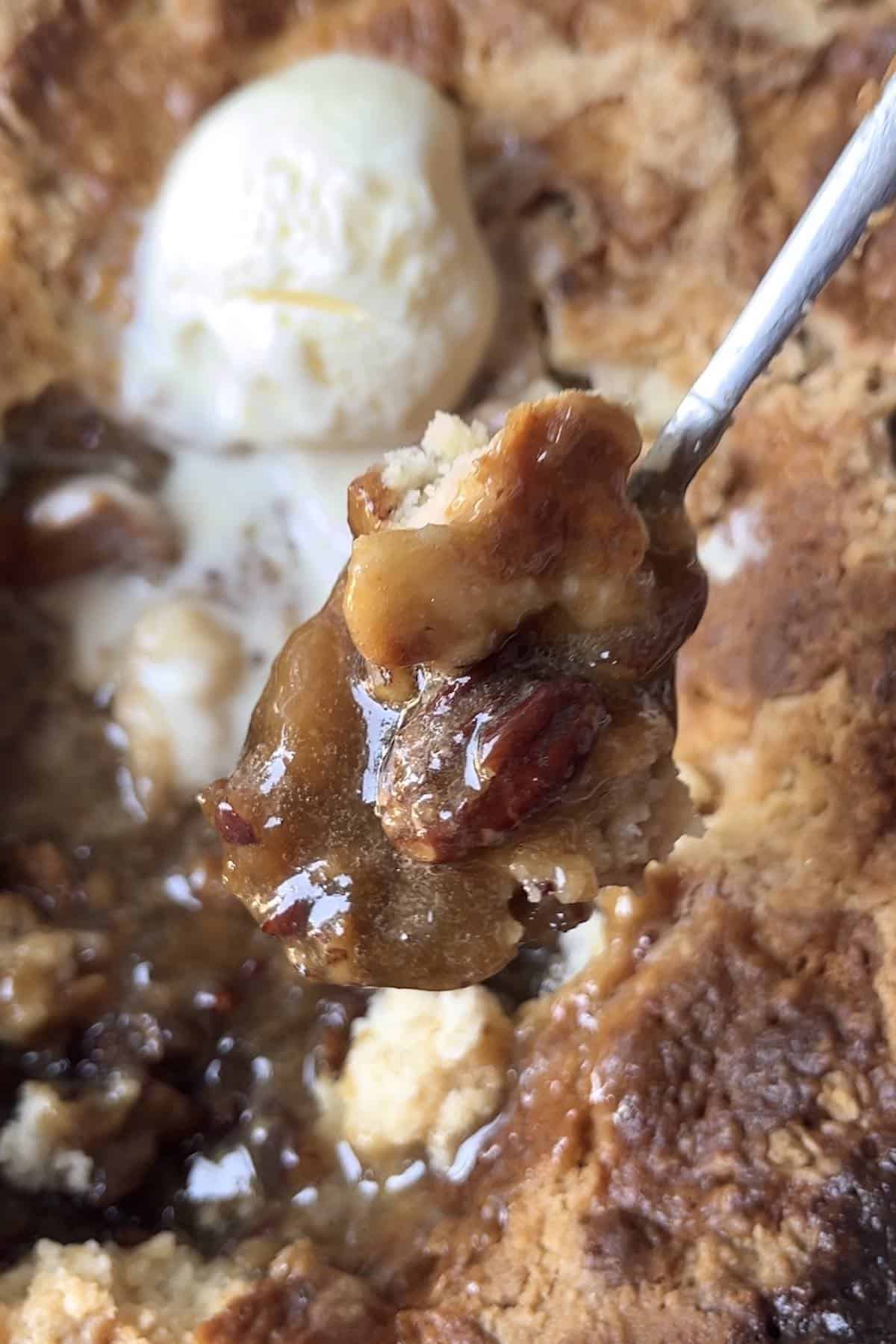Spoonful of gooey pecan pie cobbler with cake mix.