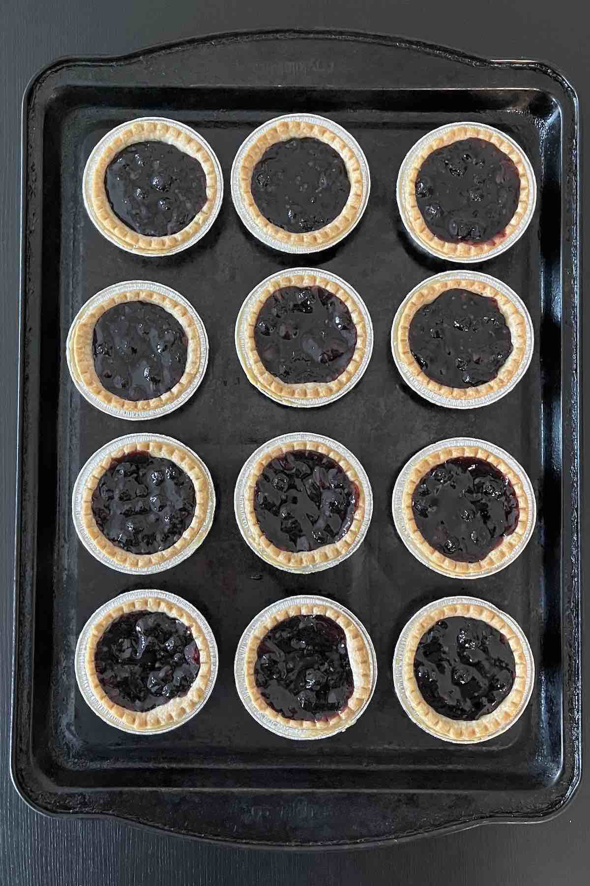 Baked blueberry tarts on a baking sheet.