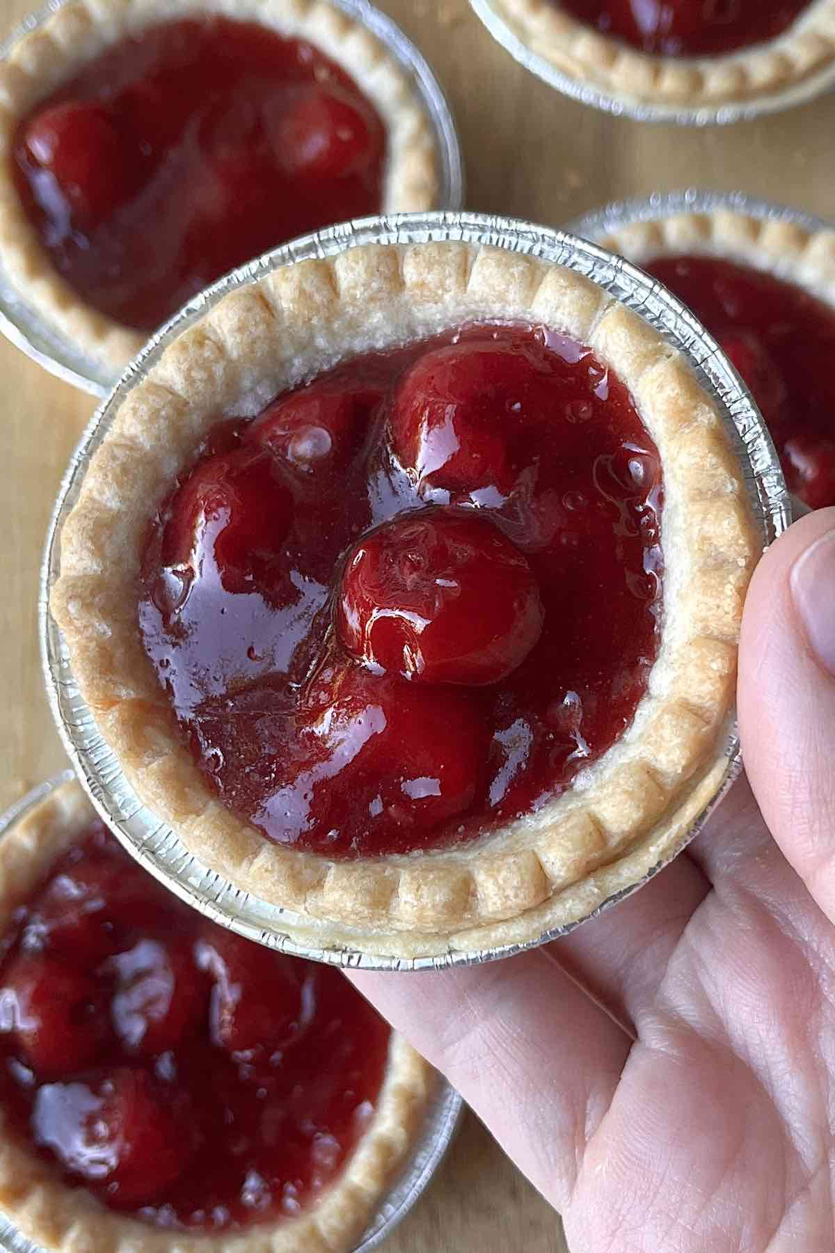 Hand holding a cherry tart.