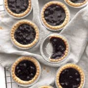Mini blueberry tarts scattered on a cooling rack.