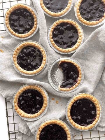 Blueberry tarts scattered on a cooling rack.