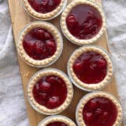 Cherry tarts scattered on a wooden serving board.