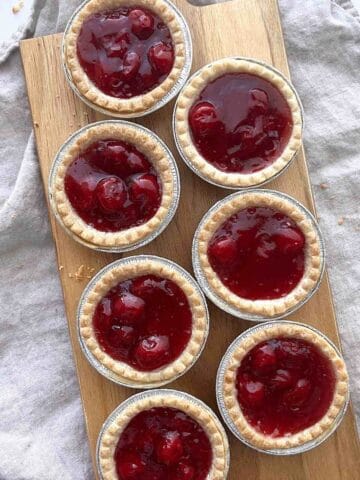Cherry tarts scattered on a wooden serving board.