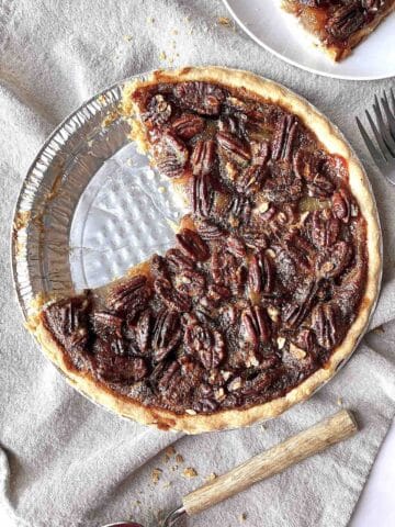 Pecan apple pie with a couple of slices missing from it.