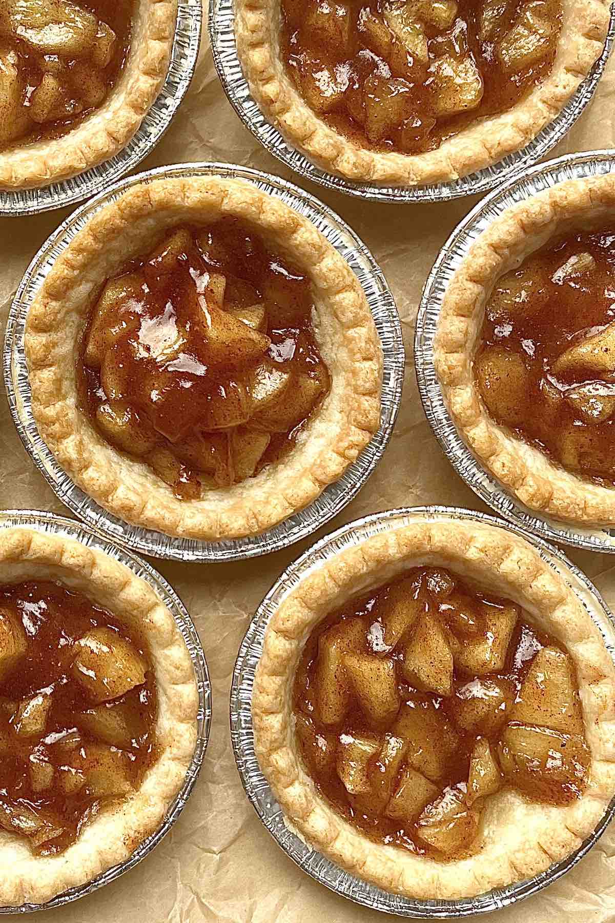 Mini apple pie tarts on a piece of crinkly brown parchment paper.