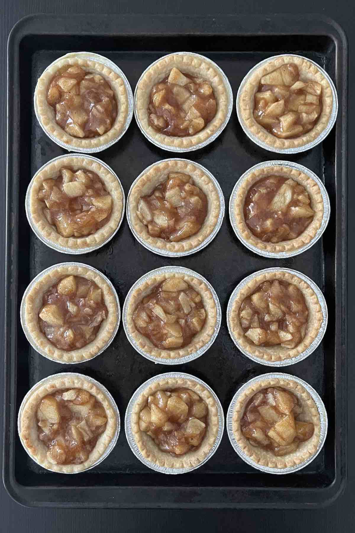 Baked apple pie tarts on a baking sheet.