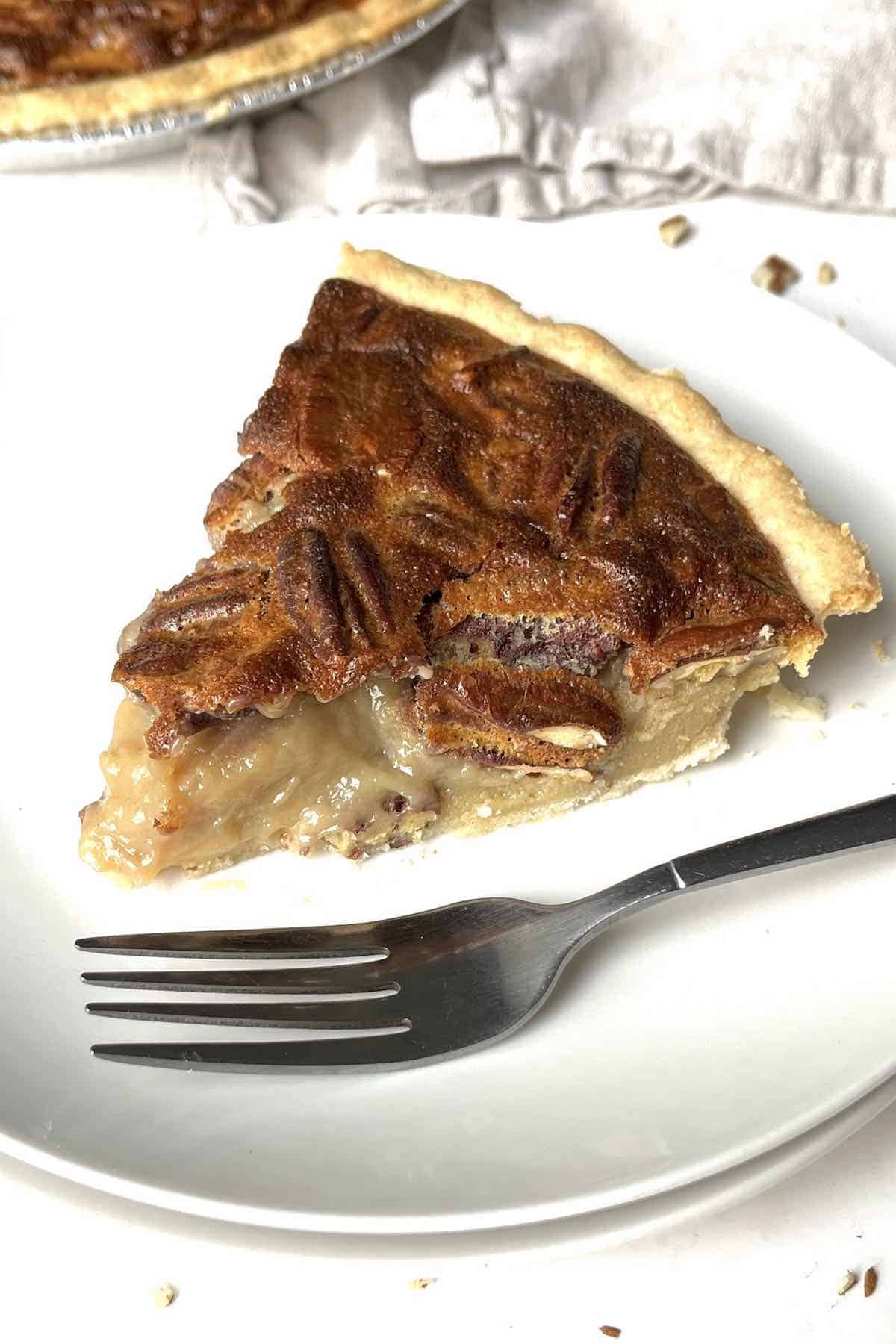 Slice of condensed milk pecan pie on a white plate.