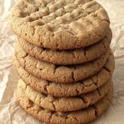 3 ingredient peanut butter cookies stacked on a piece of brown parchment paper.