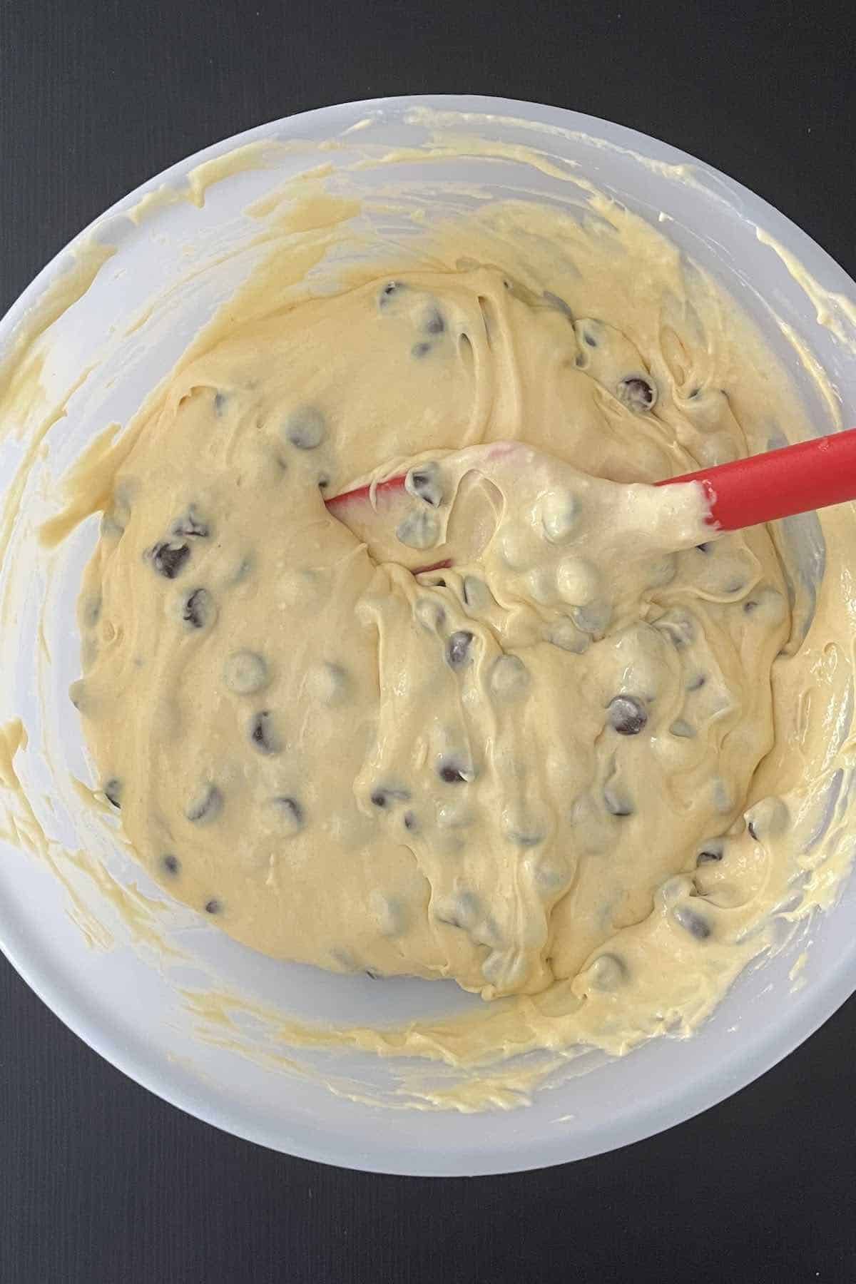 Chocolate chips folded into a bowl of muffin batter.