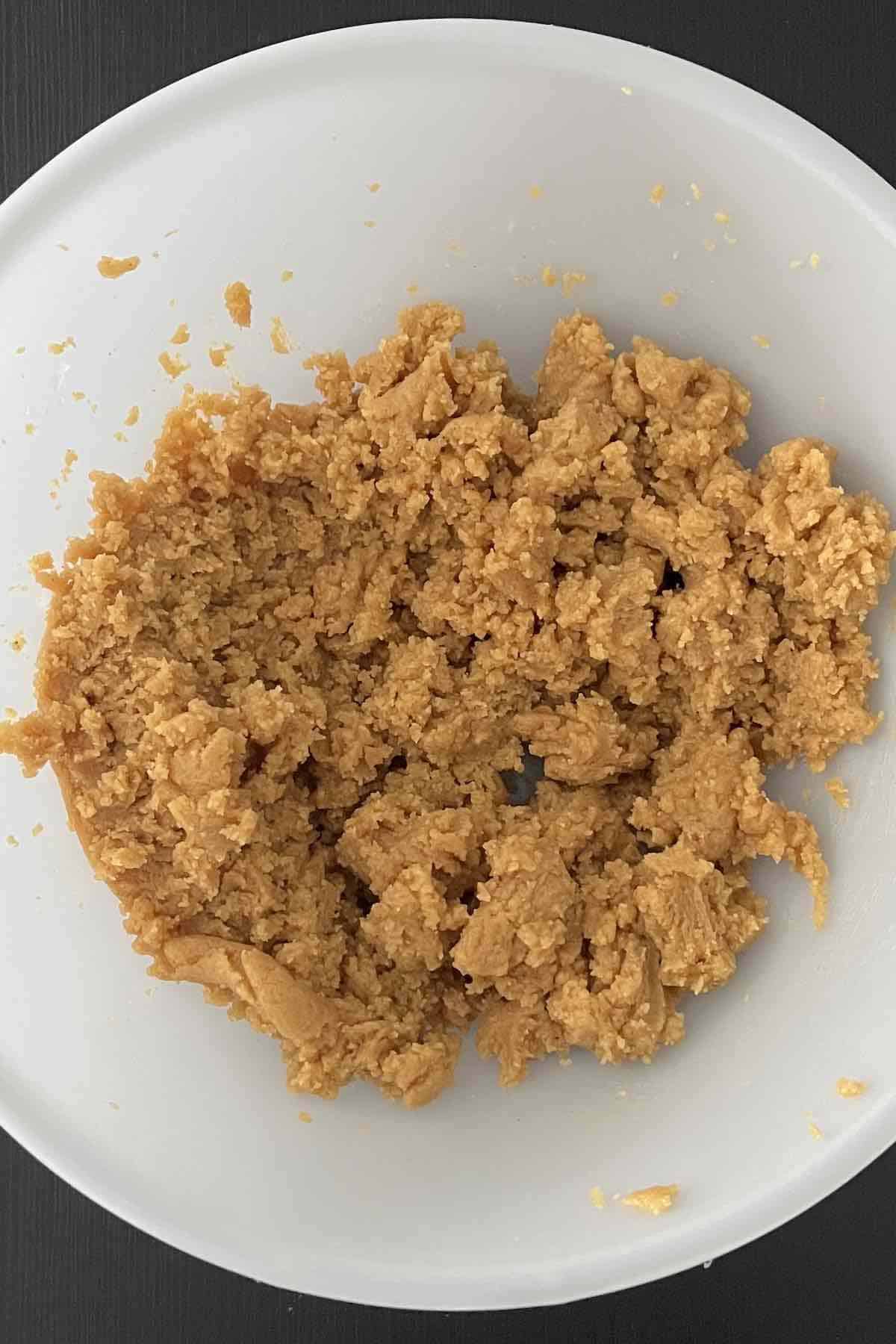 Peanut butter, sugar, and an egg mixed in the bowl.