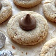 Peanut butter blossoms scattered on a piece of brown parchment paper.
