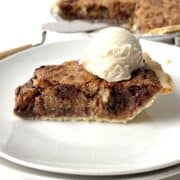 Slice of texas trash pie topped with a scoop of vanilla ice cream on a white plate.