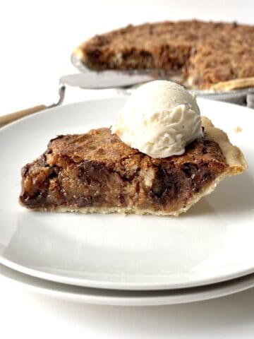 Slice of texas trash pie topped with a scoop of vanilla ice cream on a white plate.