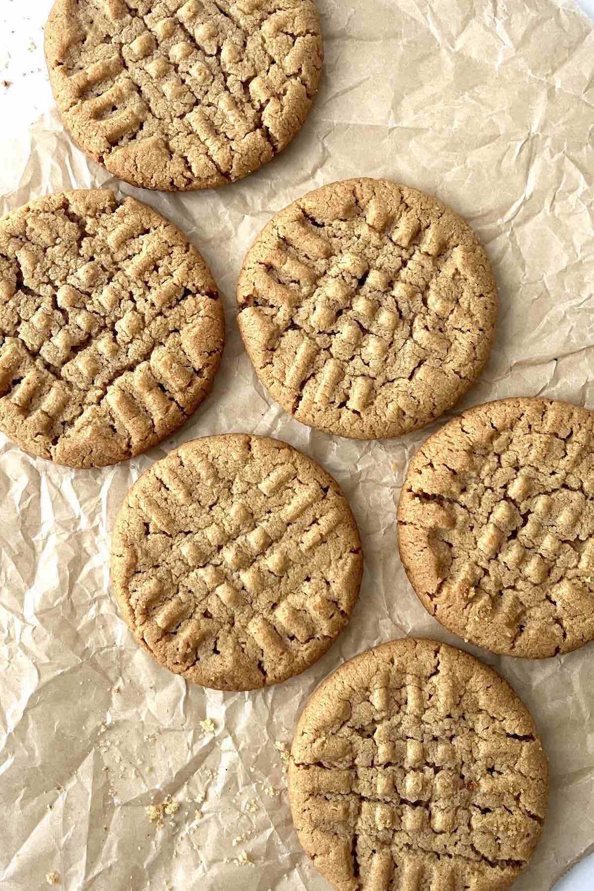 3 ingredient peanut butter cookies scattered on a piece of brown parchment paper.