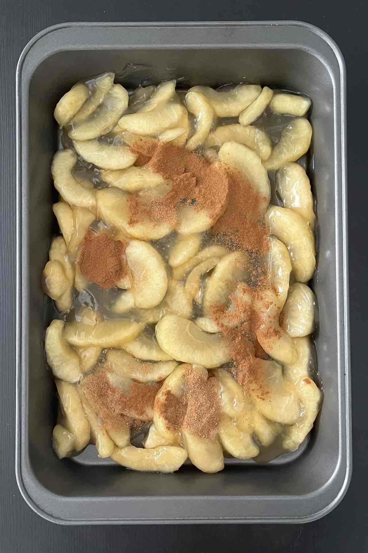 Apple pie filling, cinnamon, and nutmeg in a baking dish.