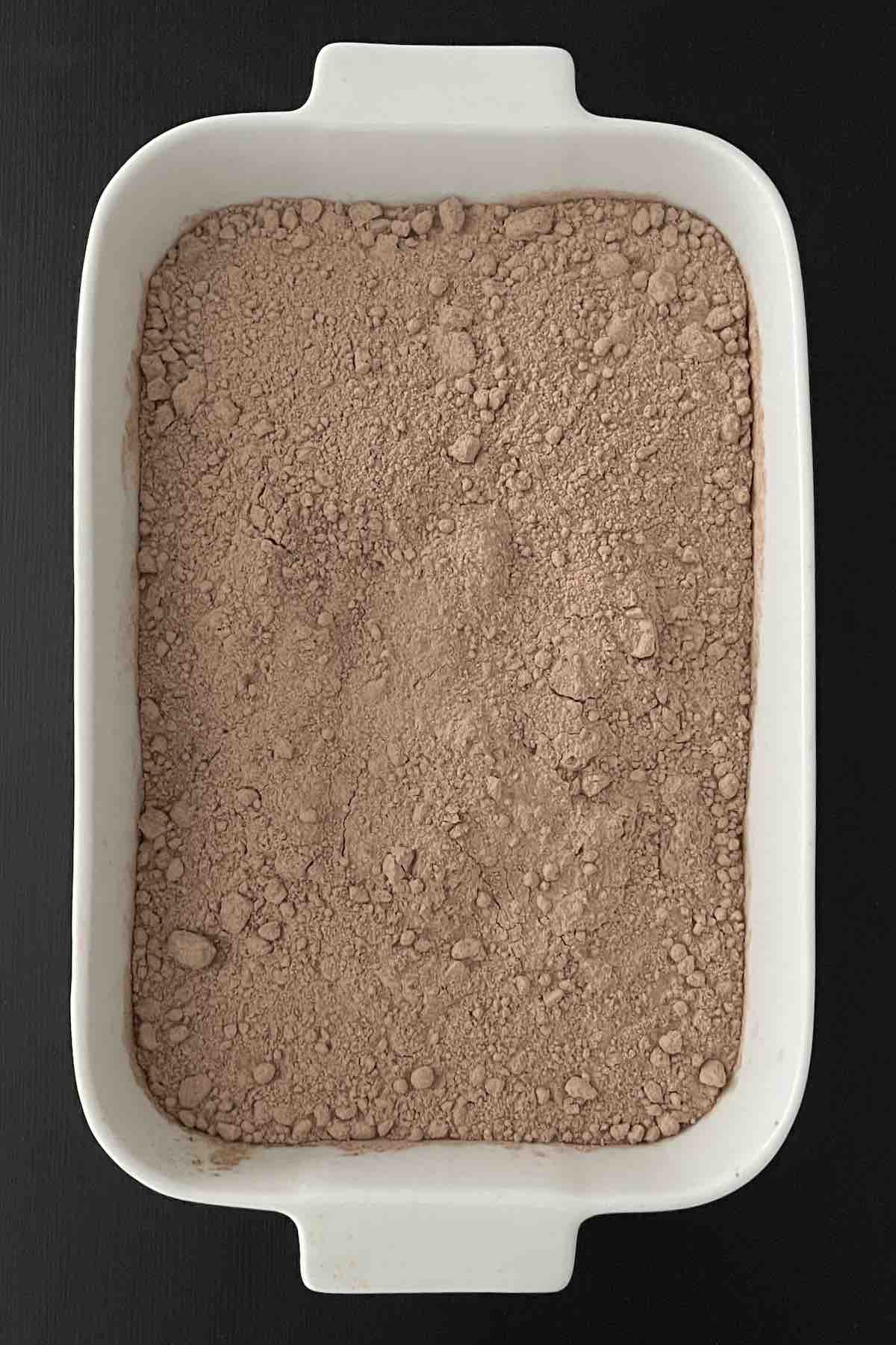 Cherry pie filling in baking dish topped with chocolate cake mix.