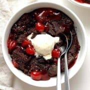 Chocolate cherry cobbler in a bowl topped with vanilla ice cream.