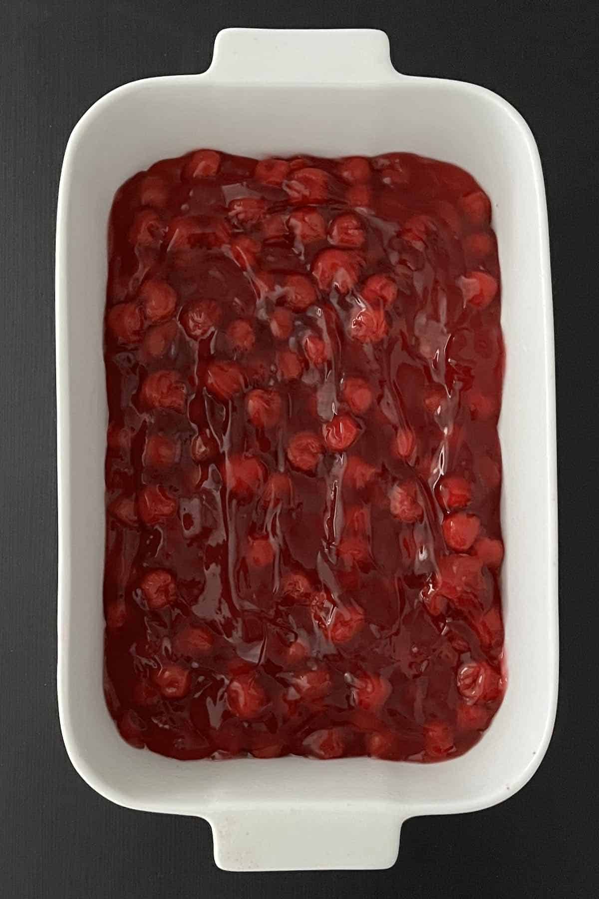 Baking dish with cherry pie filling in it.