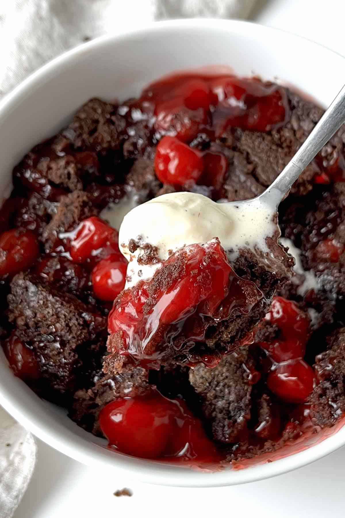 Spoon with a scoop of chocolate cherry cobbler on it.