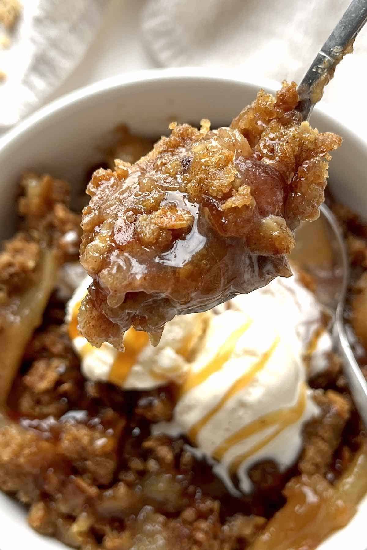Spoon with a scoop of granola apple crisp on it.