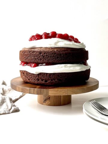 Black forest cake on a wooden cake stand.