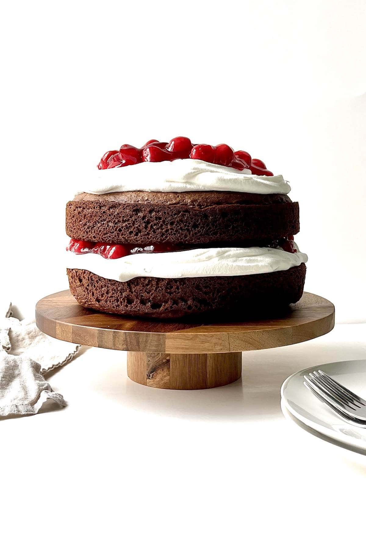Black forest cake on a wooden cake stand.