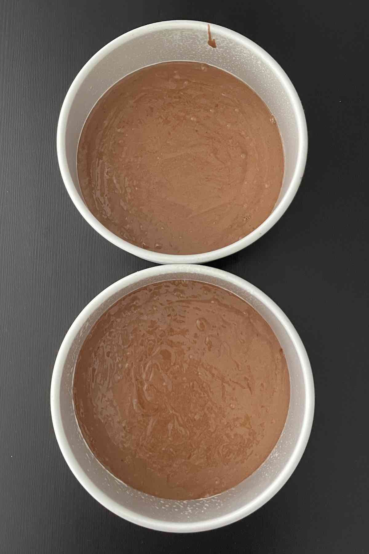Two round cake pans filled with cake batter.