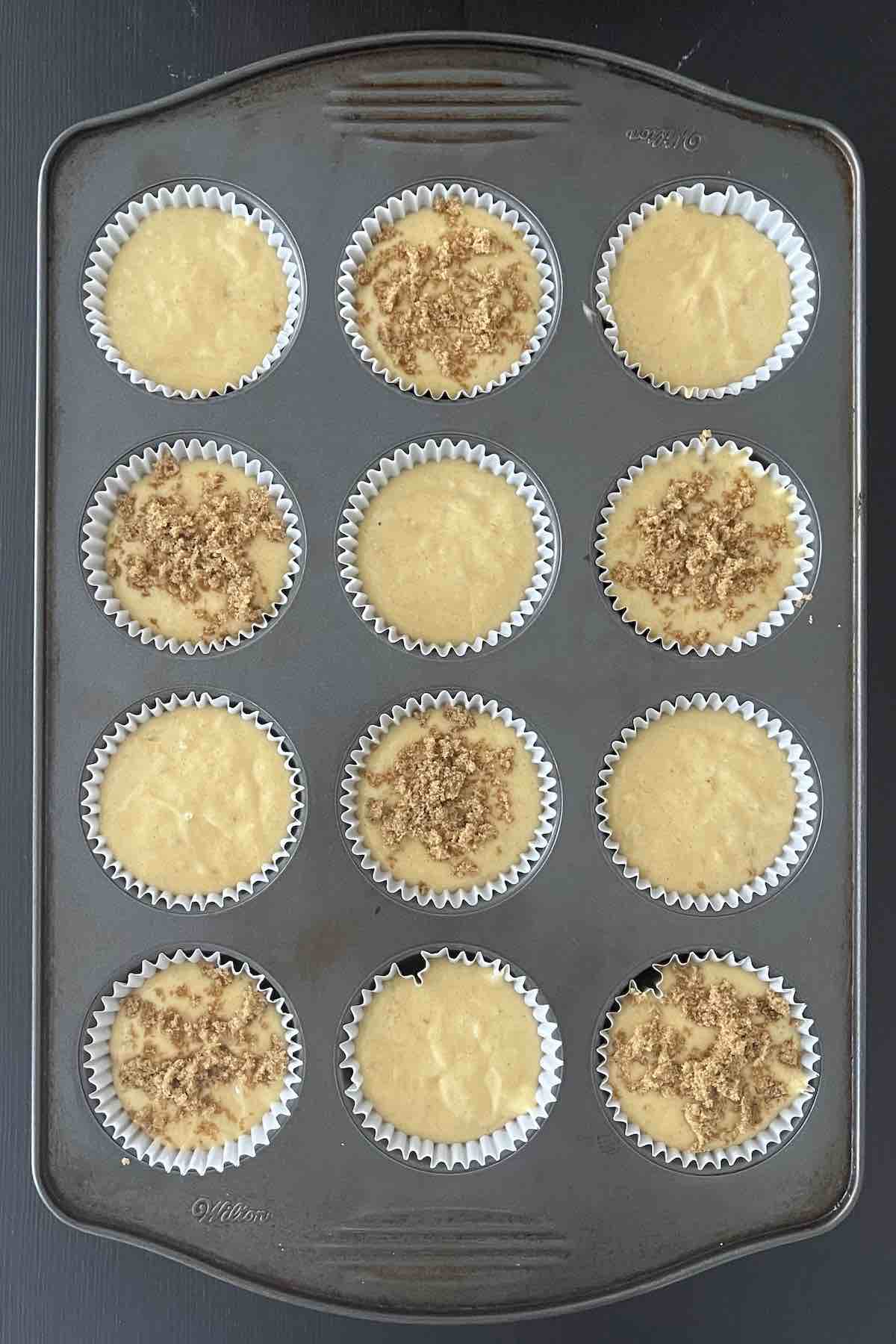 Muffin batter filled in muffin liners in a muffin pan.