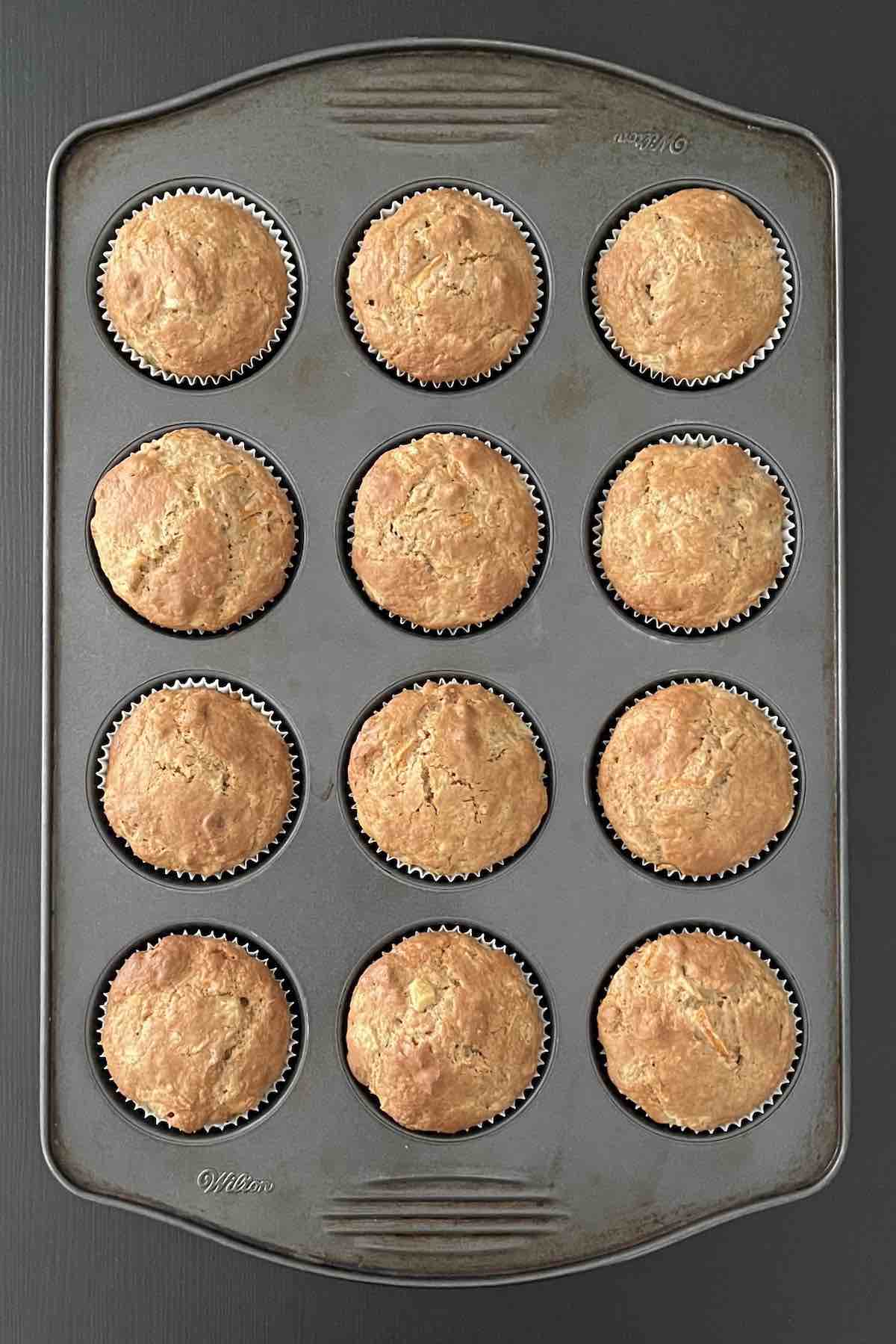 Baked carrot cake muffins in a muffin pan.