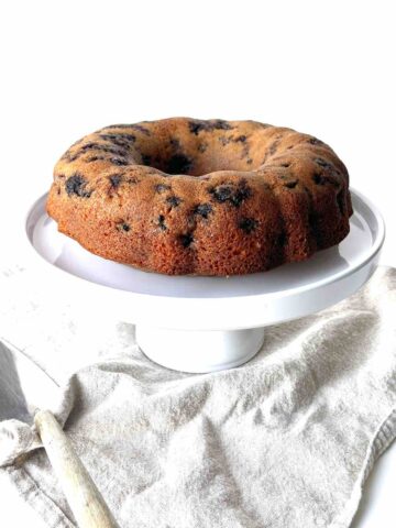 Lemon blueberry cake on a white cake stand.