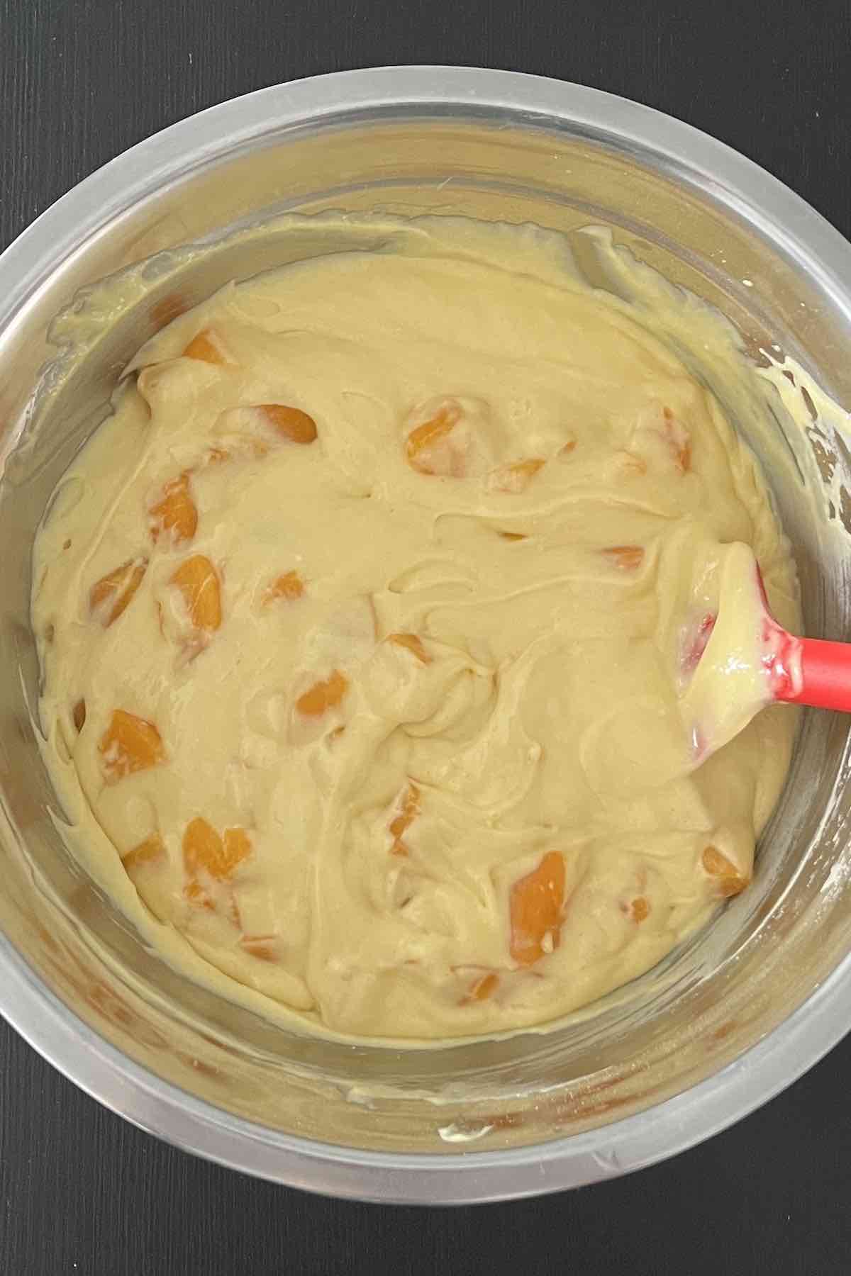 Chopped peaches folded into the cake batter in the bowl.