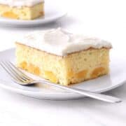 Two slices of peach cake on white plates.