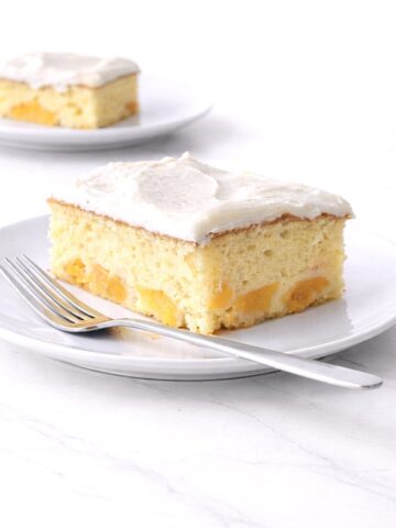 Two slices of peach cake on white plates.