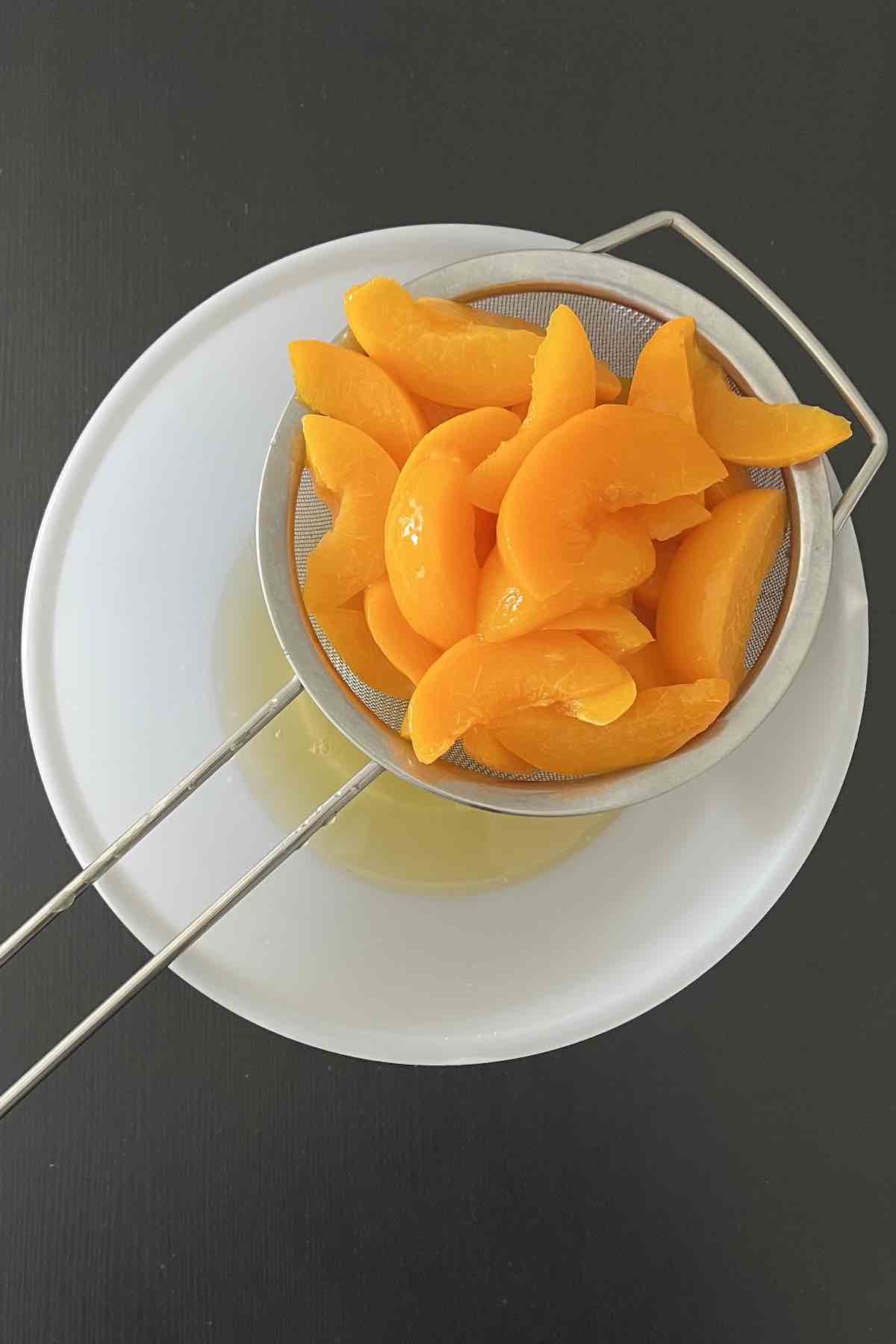 Peaches drained over bowl.