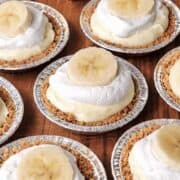 No bake mini banana cream pies scattered on a wooden table.